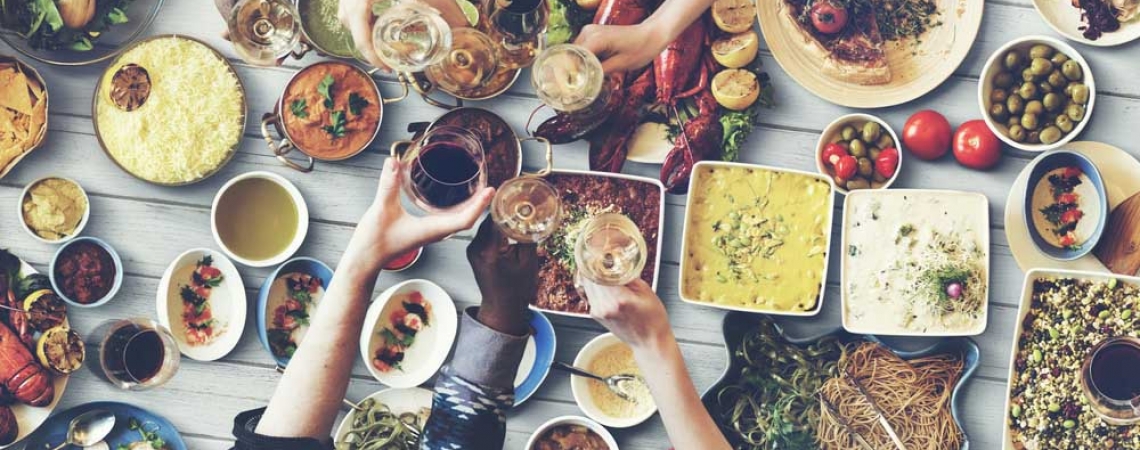 table laden with food, friends toasting